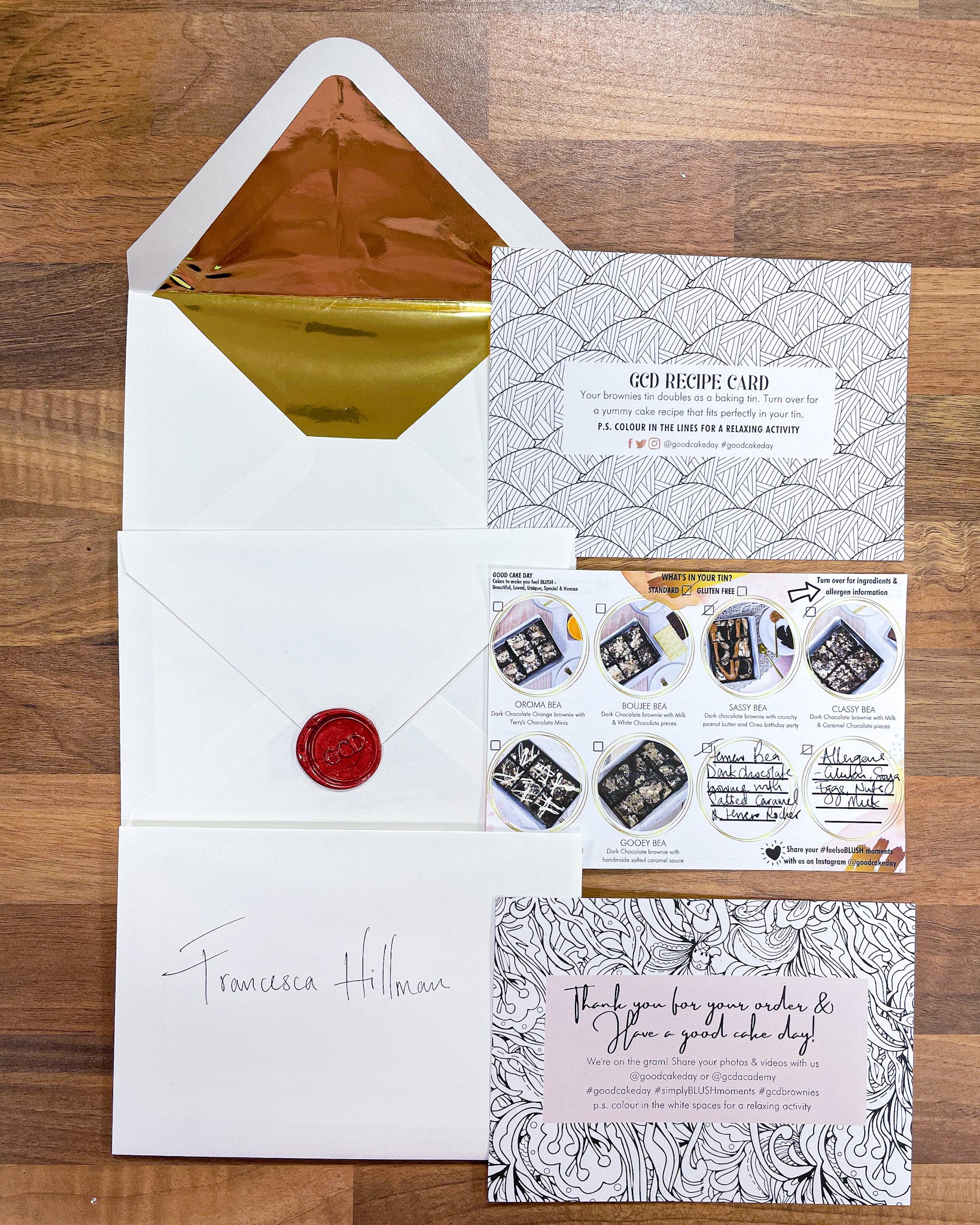 Good Cake Day Packaging comprising a recipe card that doubles as a colouring sheet, a picture allergen card, thank you card that doubles as a coloring card, gold lined cream envelope, wax sealed envelope with GCD logo