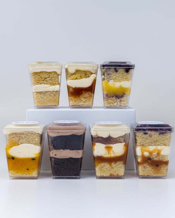 A collection of cake sample boxes presented in a eco-friendly postal box, each individual container showcasing a different cake flavor.