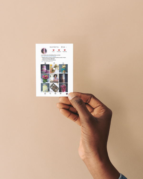 Hand holding an Instagram-style business card against a beige background