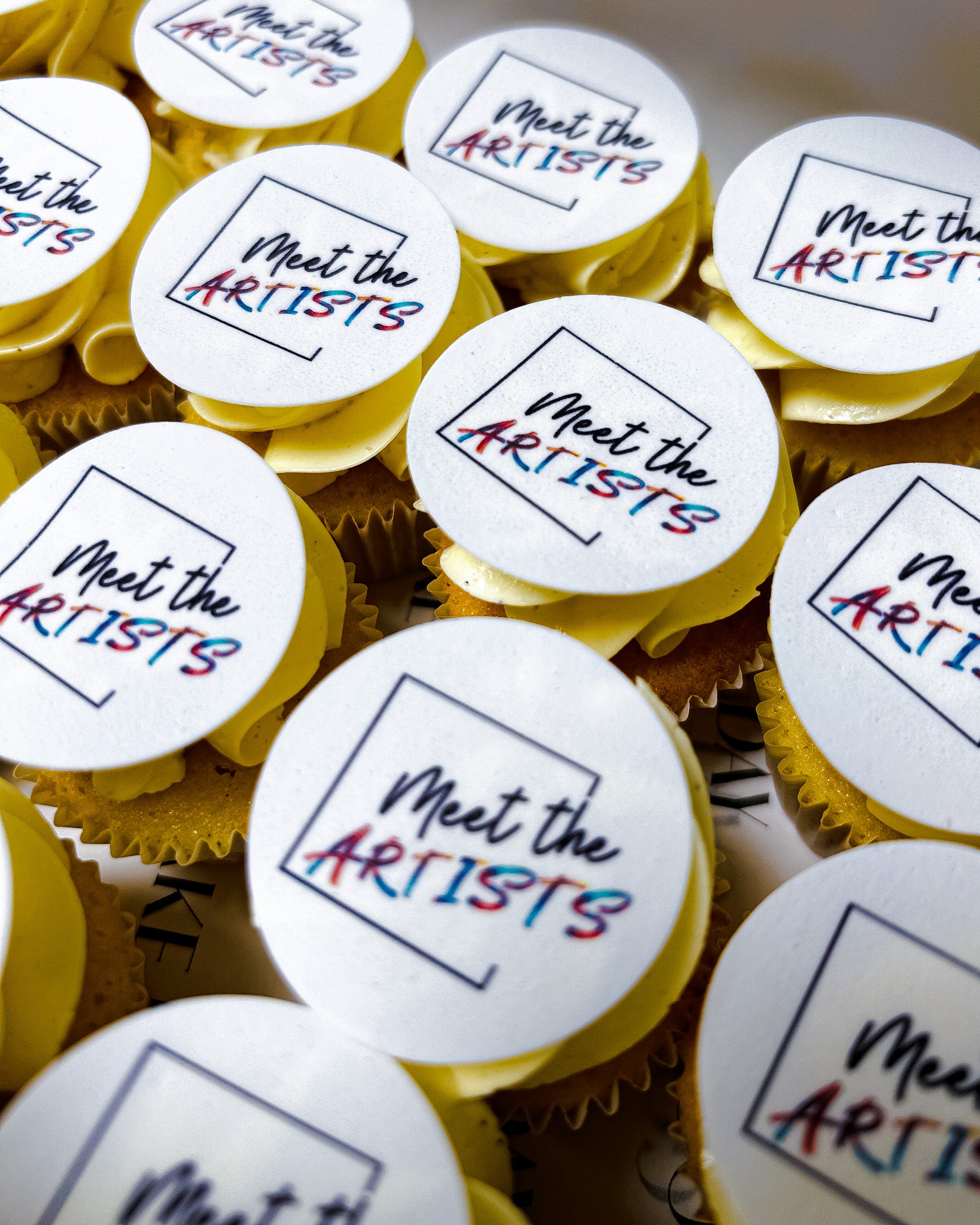 Mini cupcakes with 'Meet the Artists' toppers arranged in a pattern.