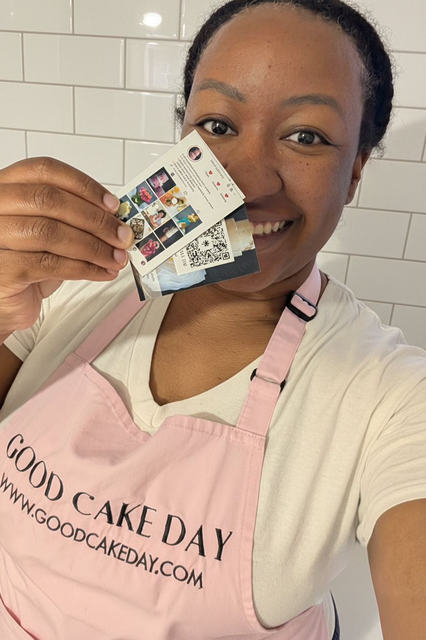 Person wearing a 'Good Cake Day' apron holding a business card.