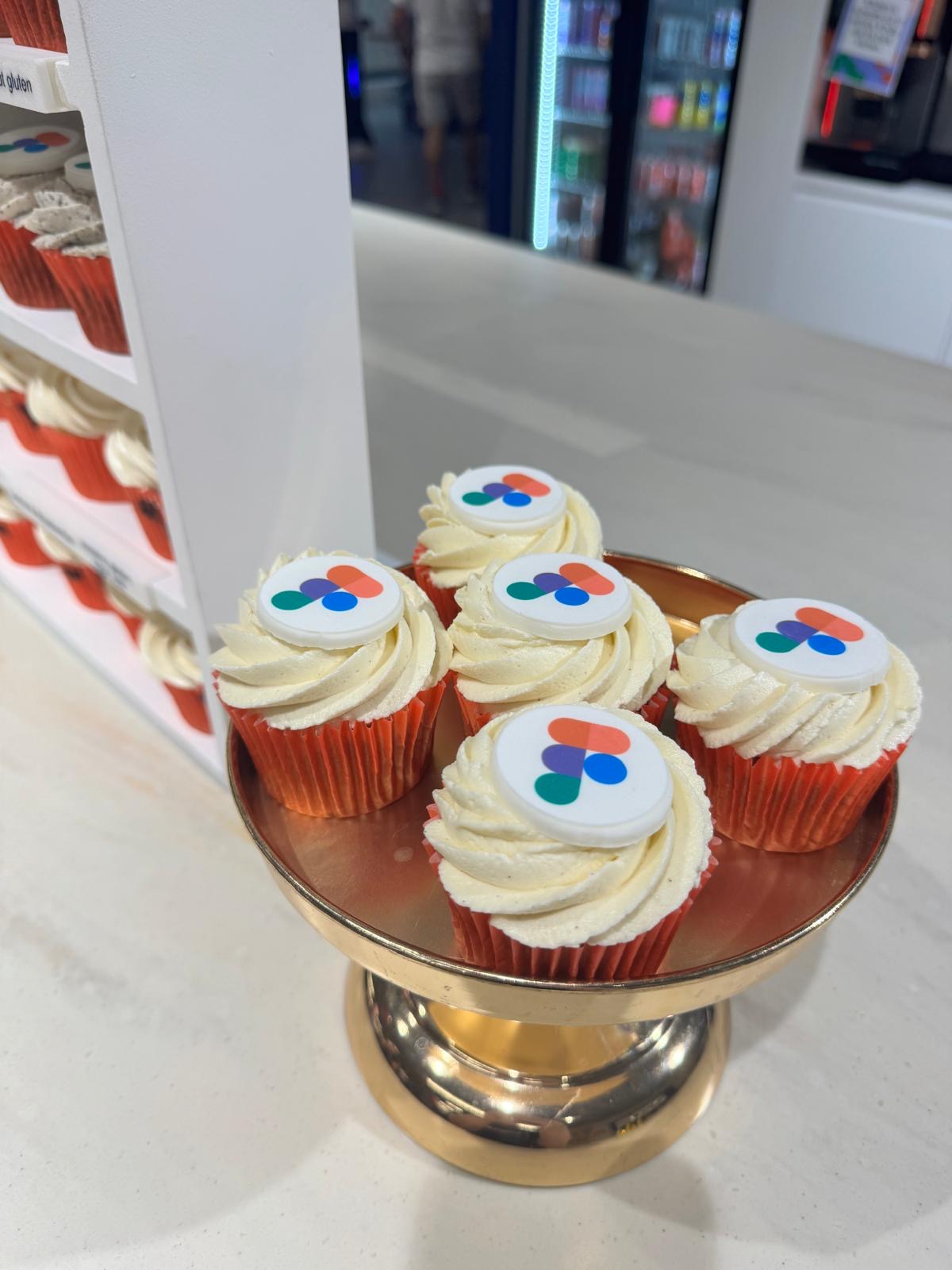 Cupcakes with Figma logo on a gold stand in a casual setting