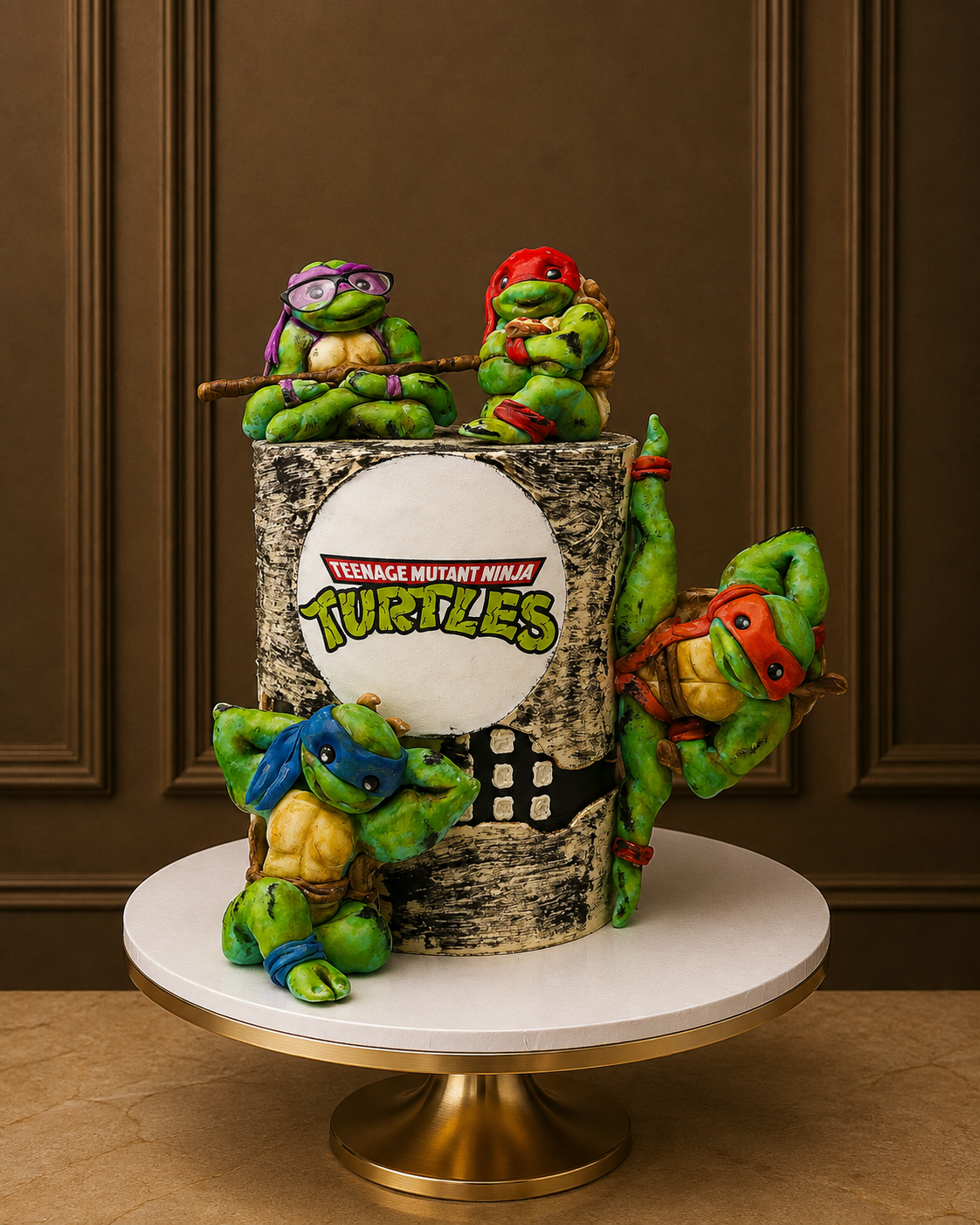 A custom 3D cake sculpted as a Teenage Mutant Ninja Turtles-themed cake stand on a white and gold pedestal. The cake features four fondant turtle figures (Leonardo, Michelangelo, Donato, and Raph) posed around a faux tree trunk base printed with the TMNT logo.