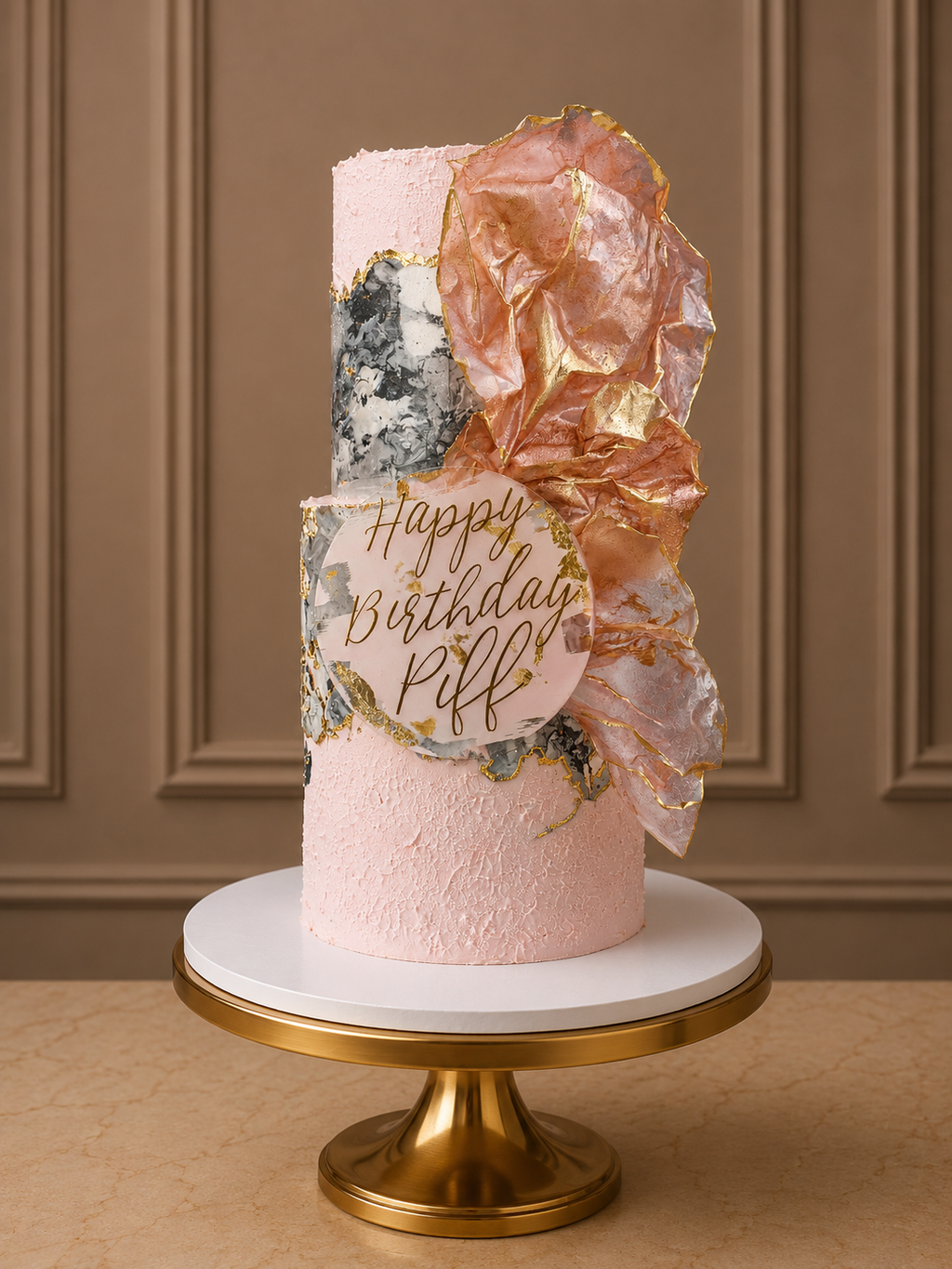 A pink frosted birthday cake with gold foil lettering reading 'Happy Birthday Piff' and a large crumpled rose-gold foil decoration, displayed on a white and gold cake stand against a brown paneled wall.