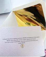 Load image into Gallery viewer, Textured white gift card in front of a gold lined envelope. 
