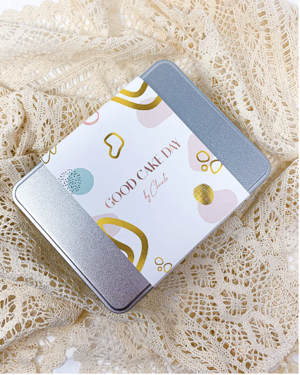 A silver rectangle food tin with a Good Cake Day sleeve across the middle of it. 